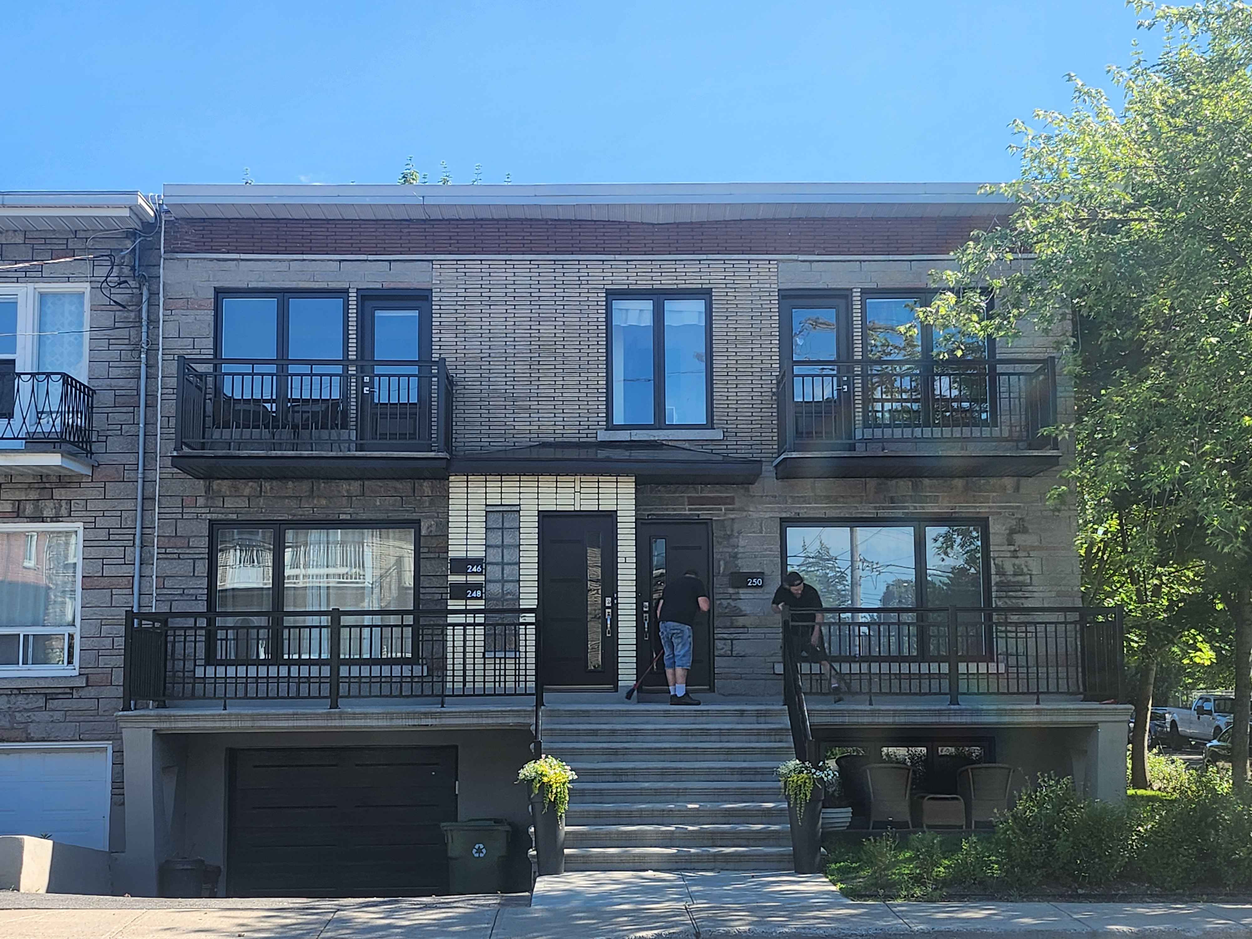 Immeuble résidentiel rénové — façade en brique avec balcons noirs modernes