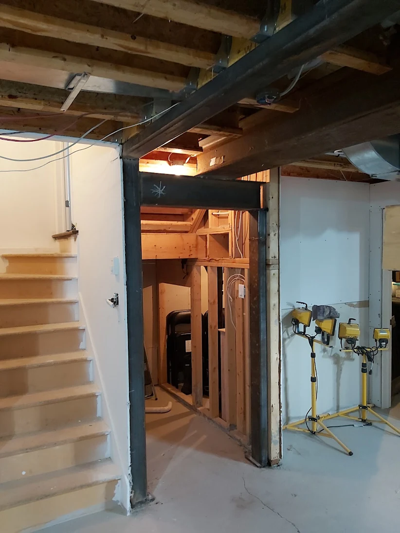 Rénovation structurale de sous-sol — poutre d'acier et ossature bois en cours de travaux